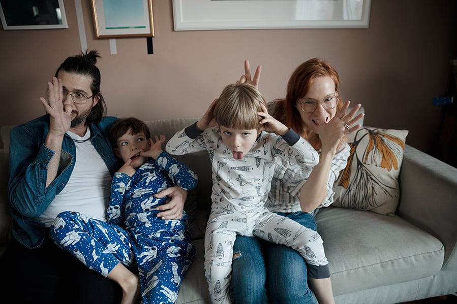 Portrait playful family making faces, gesturing on living room sofa