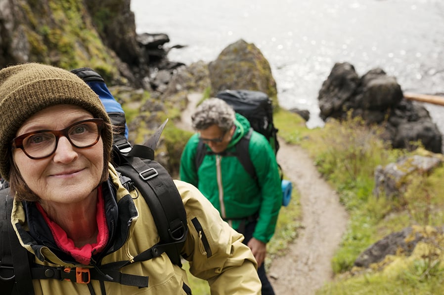 Portrait smiling, confident active senior woman backpacking with husband above ocean